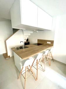 a kitchen with a wooden table and white chairs at Les Clés de Saint-Pierre in Saint-Pierre-Église