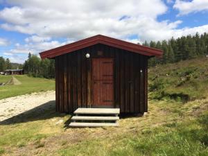 een houten buitenhuis met een houten deur en trap bij Rondane Friluftssenter Rondetunet in Brenn