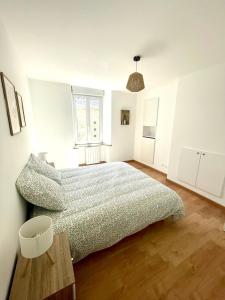 a bedroom with a bed in a white room at Les Clés de Saint-Pierre in Saint-Pierre-Église +1 photo