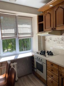 a kitchen with a stove and two windows at Апарт Безручка in Rivne