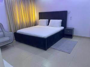 a bedroom with a large bed and a chair at Murphy Apartments, Lekki in Lekki