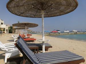 a group of chairs and umbrellas on a beach at Three-Bedroom Apartment at Louly Beach Resort in Ain Sokhna