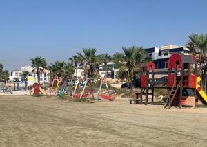 a playground on a sandy beach with palm trees at Sandy Beach Villas Sea View Apartment Pyla in Larnaka