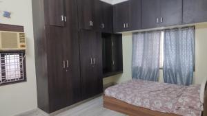 1 dormitorio con armarios de madera oscura y 1 cama en Cozy 2BHK Villa Stay, en Haidar Sāhibgūda