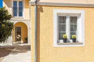 a building with two potted plants in a window at Villa Mediteran with private pool in Vrh
