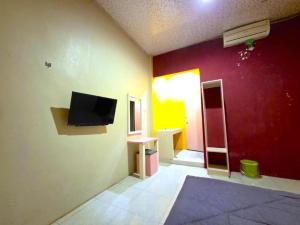 a living room with a flat screen tv on a wall at Hotel Alfatih Banda Aceh in Banda Aceh +13 photos