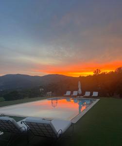 ein Pool mit Stühlen und ein Sonnenuntergang im Hintergrund in der Unterkunft Chambre d'hôtes avec jacuzzi proche Saint Tropez in Plan-de-la-Tour + 5 Fotos