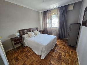 a bedroom with a white bed and a wooden floor at Casa en la playa de Panxón in Nigrán