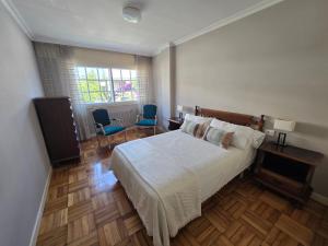 a bedroom with a bed and two chairs and a window at Casa en la playa de Panxón in Nigrán