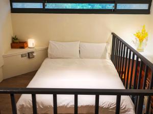 a bedroom with a bed with white sheets and a window at 好和院景 How Has in Chishang