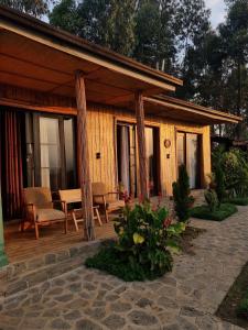a wooden cabin with a table and chairs on a patio at Khaya Nzuri Romantic Hilltop Cabin with Virunga Views in Gasanze