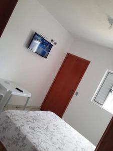 a bedroom with a bed and a tv on the wall at Hotel Santa Thereza in Bofete