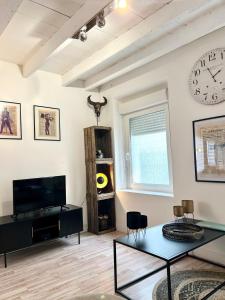 a living room with a tv and a clock on the wall at Les 2 C’ in Cayeux-sur-Mer