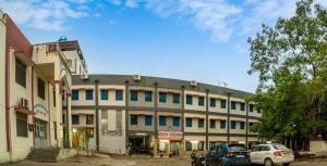 乌代浦Devdarshan Hotel & Restaurant的前面停着汽车的建筑物