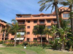 an orange building with palm trees in front of it at LM APARTAMENTOS Dos mares in Motril