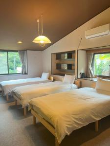 una camera con tre letti e due finestre di Sotoura Resort House 涛Tõ! BBQ-MAX10ppl-4min to Sotoura beach! a Shimoda