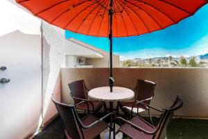 a table and chairs with a red umbrella on a balcony at Plaza Villa Downtown Condo - 2877 in Palm Springs