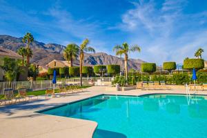 a swimming pool with palm trees and mountains in the background at Plaza Villa Downtown Condo - 2877 in Palm Springs