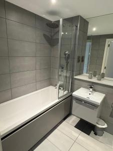 a bathroom with a bath tub and a sink at Modern 1-Bedroom Flat near NEC, Solihull in Olton