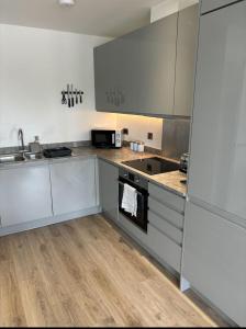a kitchen with stainless steel appliances and wooden floors at Modern 1-Bedroom Flat near NEC, Solihull in Olton