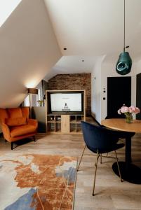 ein Wohnzimmer mit einem TV, einem Tisch und einem Stuhl in der Unterkunft Hotel Bergo Resort & SPA in Szklarska Poręba