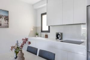 a kitchen with white cabinets and a table with flowers at 2BD Coastal Gem with Pool & Terrace - Torre de la Horadada in Torre de la Horadada +35 photos