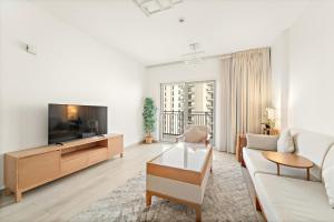 a living room with a couch and a tv at FIRST CLASS 1BR Tranquility in Style in Abu Dhabi