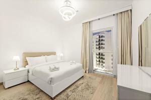 a white bedroom with a white bed and a window at FIRST CLASS 1BR Tranquility in Style in Abu Dhabi +27 photos