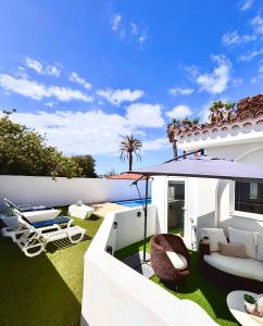 a backyard with a patio with chairs and avisor at Apartment in villa - RELAXING POOL-FRONT, PRIVATE TERRACE & POOL ACCESS, SOUTH TENERIFE in Arona