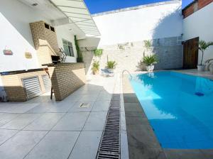 a swimming pool next to a building with a house at Cantinho Azul do Sol in Queimados