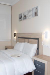 a bedroom with a white bed and two night stands at En el centro, garaje privado y terraza in O Grove