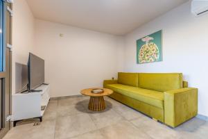 a living room with a yellow couch and a tv at Azure Sofia - Grounded in Kos