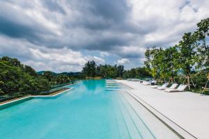 a large swimming pool with lounge chairs and trees at Beachside Residences by NLA in Bang Tao Beach