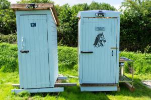 two blue portable toilets sitting in the grass at The gypsy wagon in Berwick Saint John