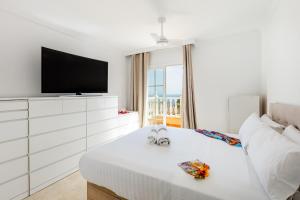 a white bedroom with a tv and a white couch at Exclusive Villa FRANJULY Playa Paraiso Ocean View Private Pool Large Terrace in Adeje +33 photos