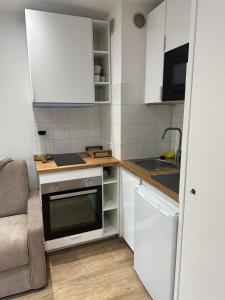 a small kitchen with white cabinets and a sink at Eden des neige in Vars +8 photos