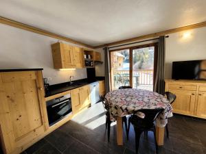 eine Küche mit einem Tisch, einem kleinen Tisch und einem TV in der Unterkunft Résidence Le Criterium - Résidence Le Critérium 3Chalet E Appartement 3 MAE-1913 in Les Champs