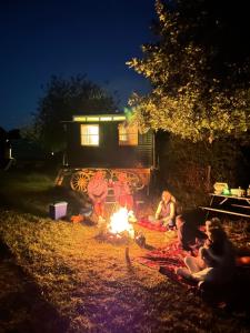 a group of people sitting around a fire at night at Prize fighter wagon in Berwick Saint John