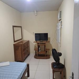 a bedroom with a bed and a tv and a chair at Casa Grande in Ananindeua