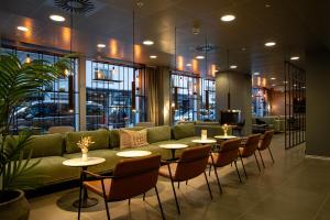 a lobby with a green couch and tables and chairs at Cabinn Plus Esbjerg in Esbjerg