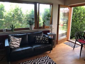a black leather couch in a living room with windows at Dreiland Fewo mit großem Freisitz in Rheinfelden