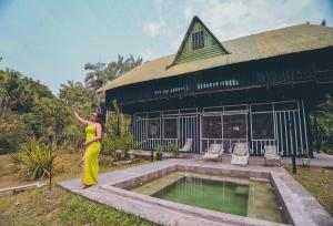 a woman in a yellow dress standing next to a pool at Ecolodge Zuruma in Leticia