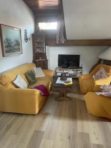 a living room with two yellow couches and a television at Mansarda Cadore in Pieve di Cadore