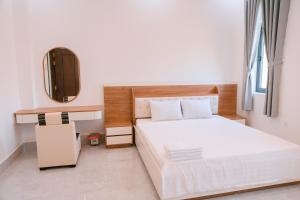 a bedroom with a white bed and a mirror at Sunny Villa Hà Tiên in Ha Tien