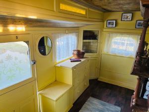 a yellow room with a cabinet and a window at The showman wagon in Berwick Saint John