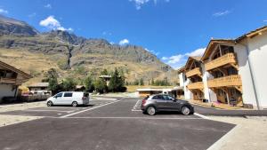 two cars parked in a parking lot in front of mountains at Résidence Cokott - 2 Pièces pour 4 Personnes MAE-2603 in Bessans +3 photos