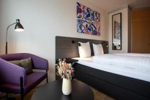 a hotel room with a bed and a chair and a table at Cabinn Plus Esbjerg in Esbjerg +36 photos