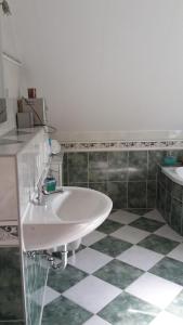 a bathroom with a white sink and a tiled floor at Messe- und Gästezimmer in Hannover