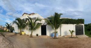 une maison blanche avec des palmiers devant dans l'établissement La Villeneuvoise, à Mbour