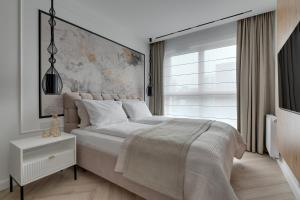 ein Schlafzimmer mit einem großen Bett und einem großen Fenster in der Unterkunft Porto Letnica Apartments with Gym & Parking by Lion Apartments in Danzig